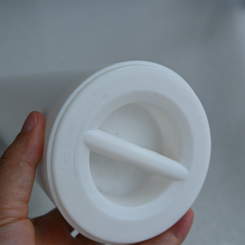 White plastic component held by a hand against a neutral background