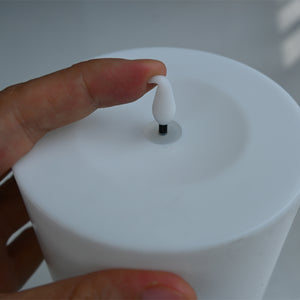 White cylindrical container with a black and white nozzle held by a hand against a light background