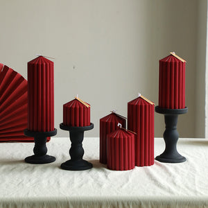 Set of red hexagonal candles on black candlesticks against a neutral background