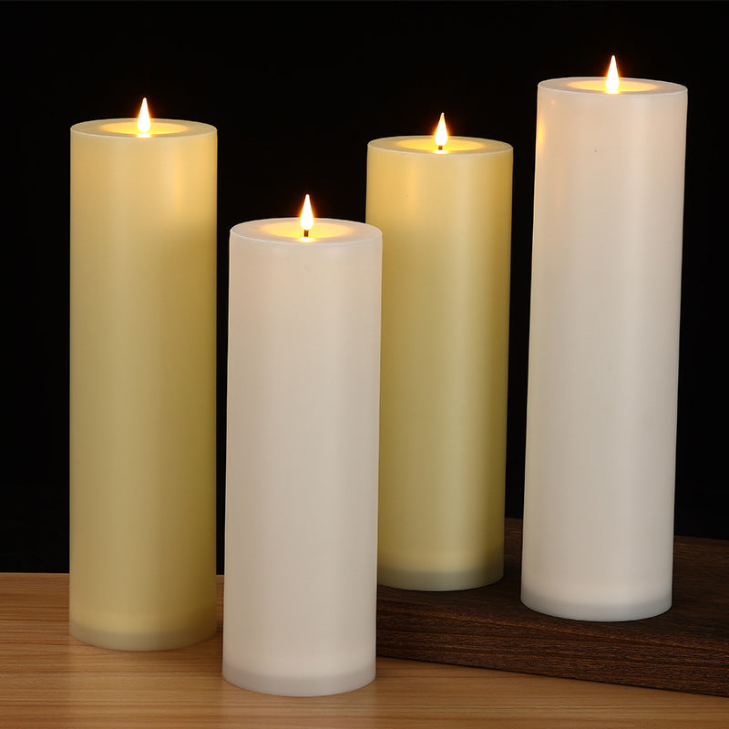 Four lit candles of different heights on a wooden surface with a dark background