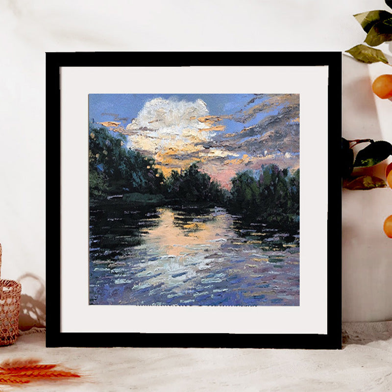 Framed painting of a sunset over a river with trees
