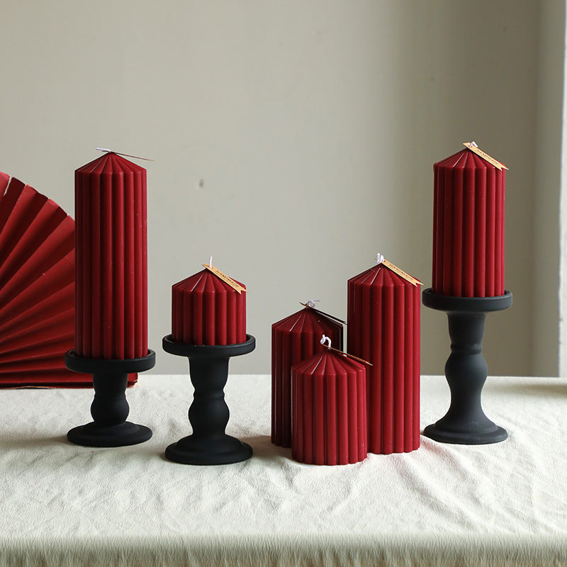 Set of red hexagonal candles on black candlesticks against a neutral background