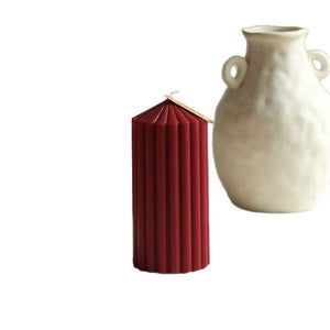 Red pleated candle and white vase on a white background